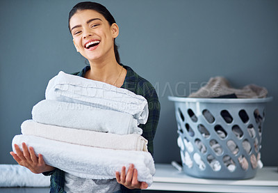 Buy stock photo Cropped portrait of an attractive young woman carrying a pile of towels while doing laundry at home