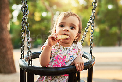 Buy stock photo Girl, baby and outdoor in swing at park, garden and eating cookies with fun, learning and balance on vacation. Child, toddler and playful with snack for development, growth and sunshine in Germany