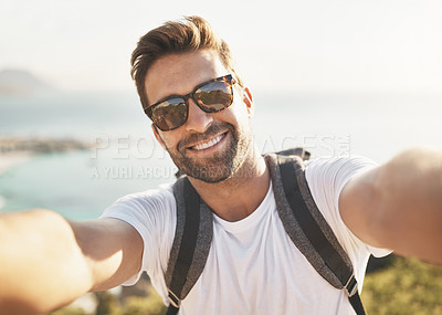 Buy stock photo Cropped portrait of a handsome young man taking selfies while hiking in the mountains