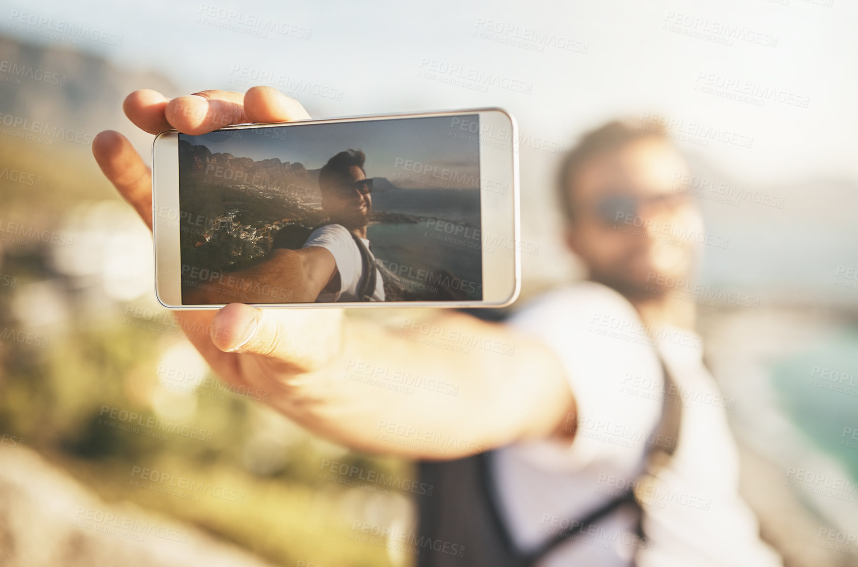 Buy stock photo Cropped shot of a handsome young man taking selfies while hiking in the mountains