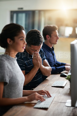 Buy stock photo Shot of a young businessman blowing his nose while working alongside his colleagues in an office