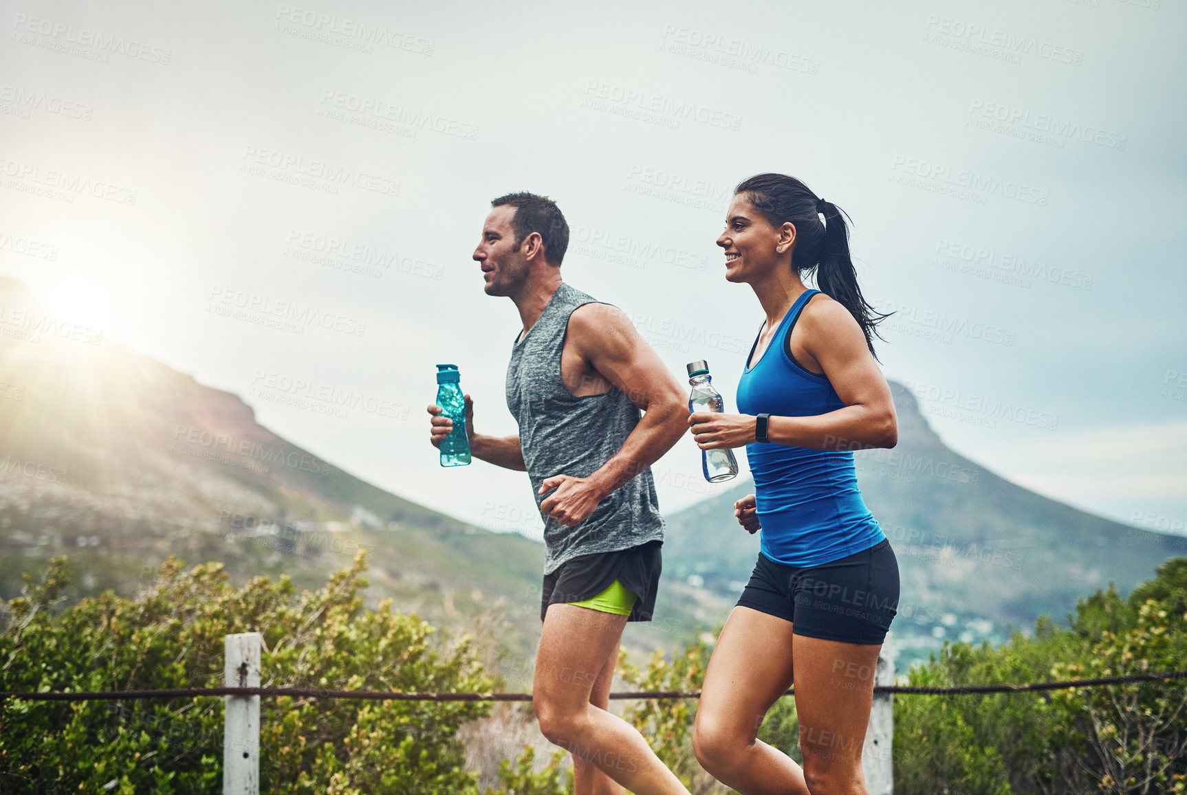 Buy stock photo Couple, people and smile with running for fitness or training, support and love in Brazil. Workout, exercise and outdoor with jogging for health, wellness and wellbeing in sunset with lens flare