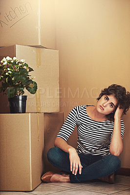Buy stock photo Shot of a young woman sitting on the floor and looking sad on moving day