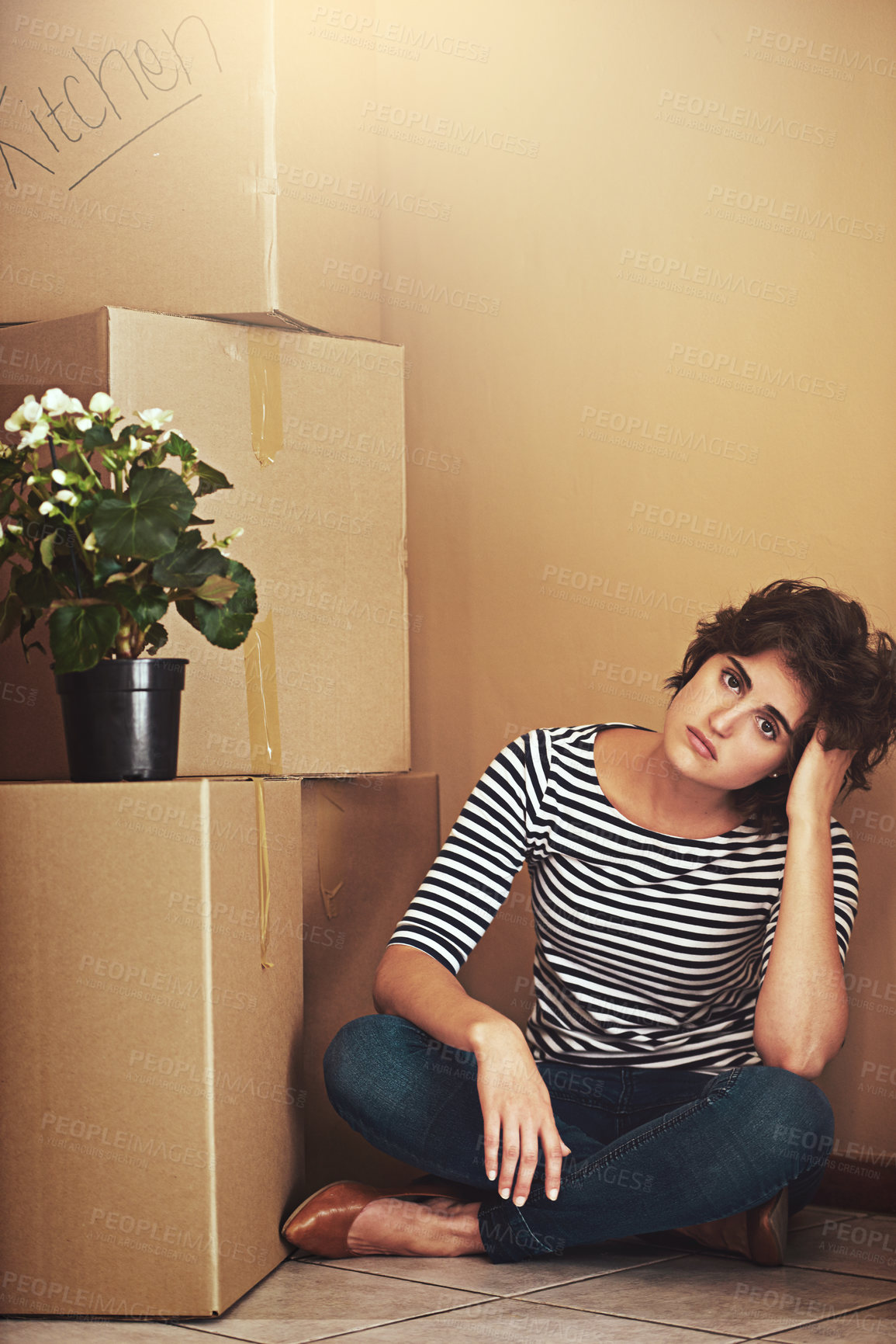 Buy stock photo Shot of a young woman sitting on the floor and looking sad on moving day