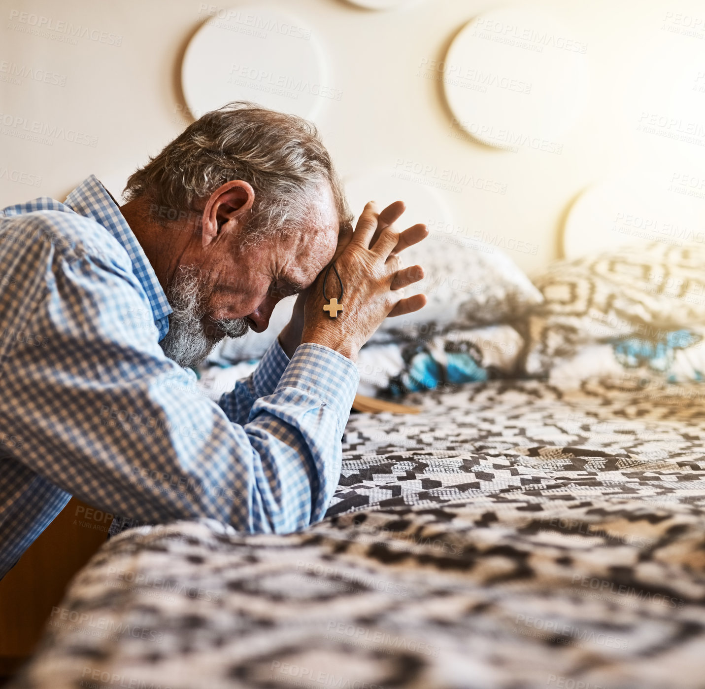 Buy stock photo Shot of a peaceful senior man kneeling next to his bed and praying with his eye's closed