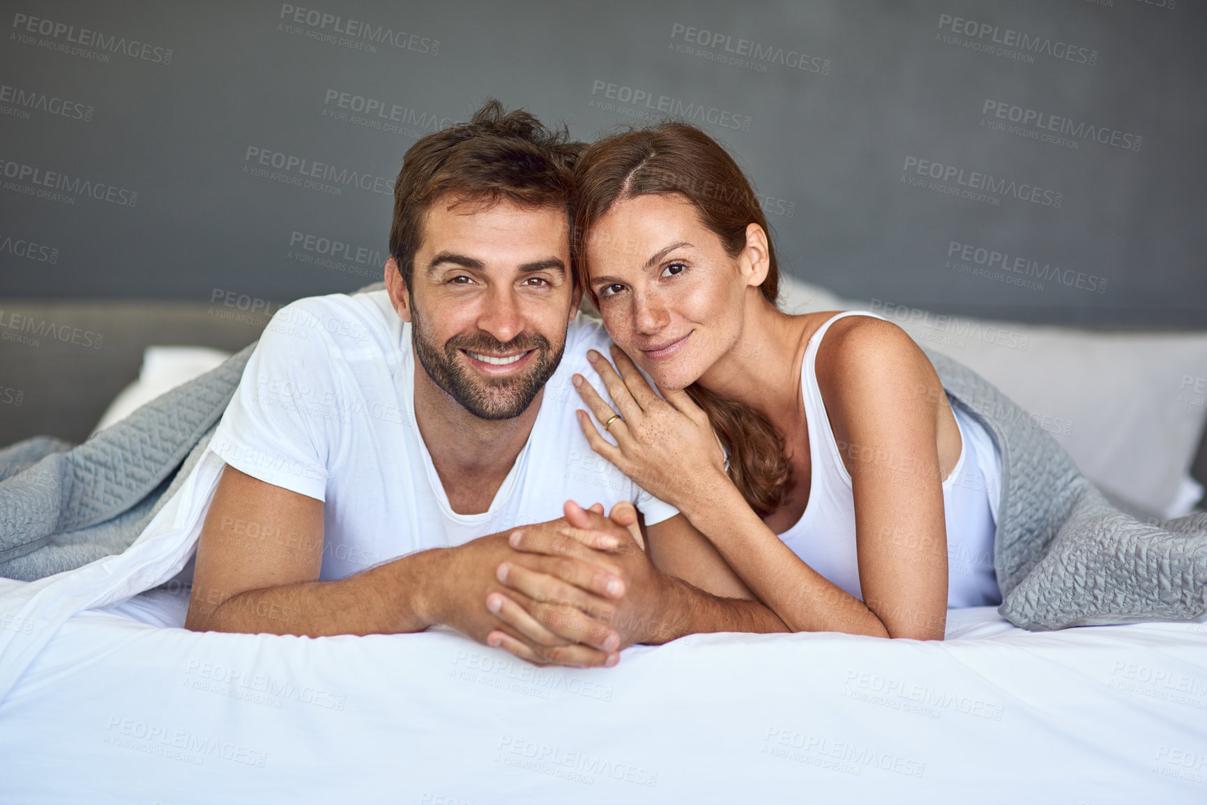 Buy stock photo Shot of a happy young couple relaxing in bed together at home