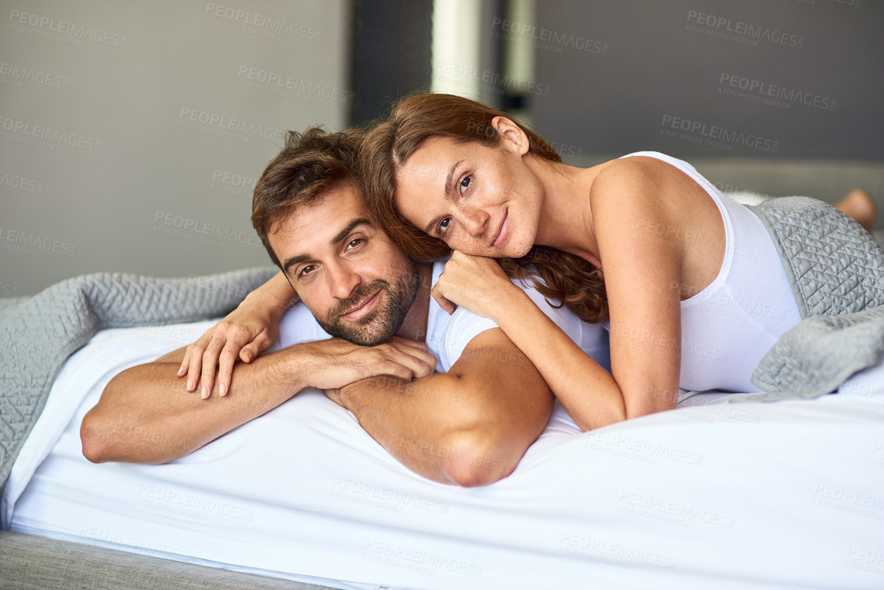 Buy stock photo Shot of a happy young couple relaxing in bed together at home