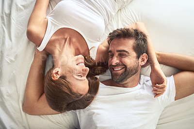 Buy stock photo High angle shot of a happy young couple relaxing in bed together at home