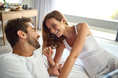 Buy stock photo Shot of a happy young couple having a playful moment in bed