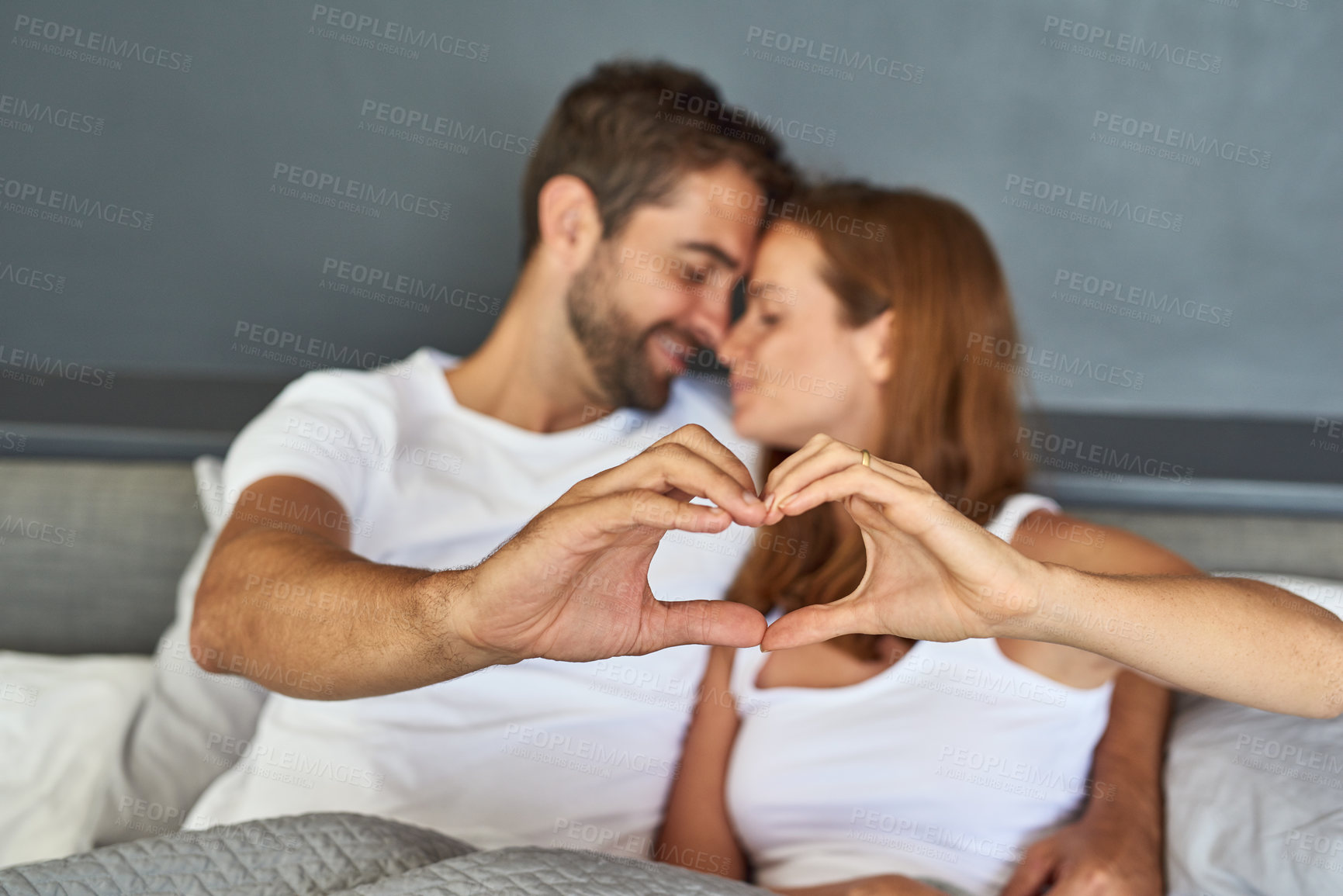 Buy stock photo Relax, couple and hands with heart in bedroom for healthy connection, commitment and trust in marriage. Woman, man and smile with love emoji at home for romance, appreciation and gratitude together