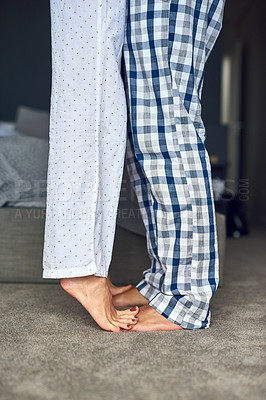 Buy stock photo Cropped shot of a loving couple standing barefoot on each others feet in the bedroom