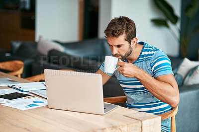 Buy stock photo Cropped shot of a handsome young male entrepreneur drinking coffee while working from his home office