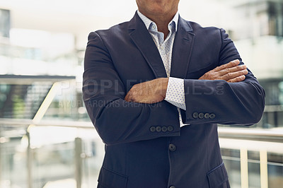 Buy stock photo Cropped shot of an unrecognizable businessman standing with arms folded inside of a building