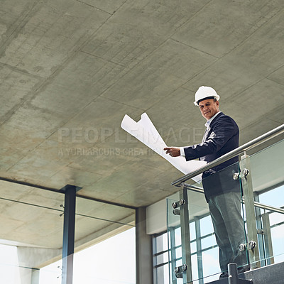 Buy stock photo Portrait of a cheerful professional male architect looking at the camera while holding blueprints inside a building