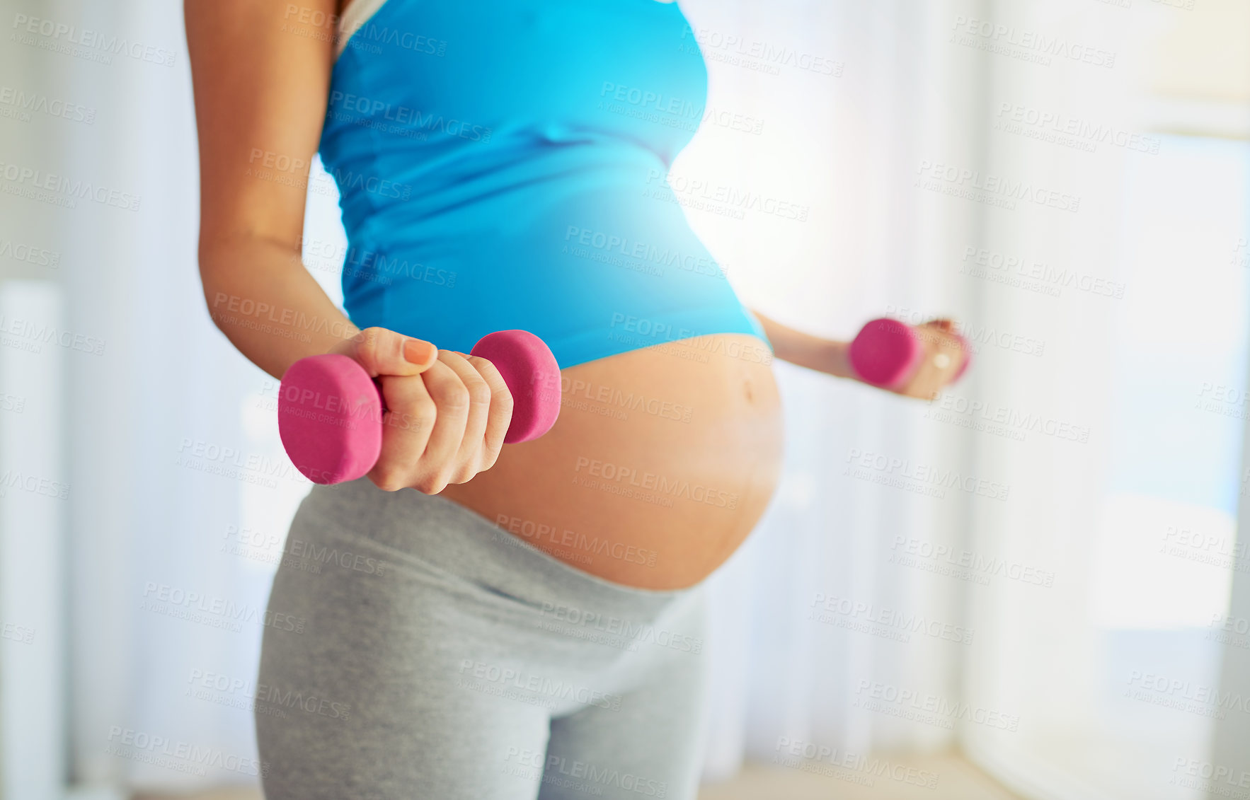 Buy stock photo Cropped shot of a pregnant woman working out with weights at home