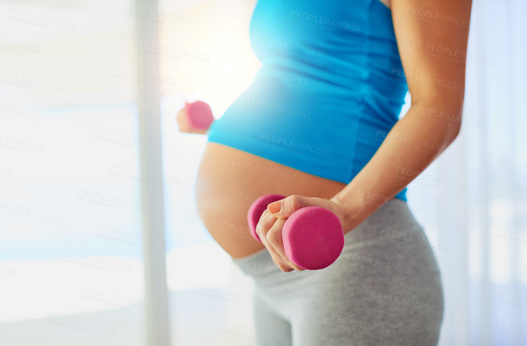 Buy stock photo Cropped shot of a pregnant woman working out with weights at home