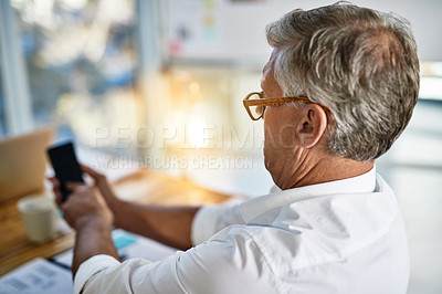 Buy stock photo Shot of a mature businessman struggling to use his cellphone in the office
