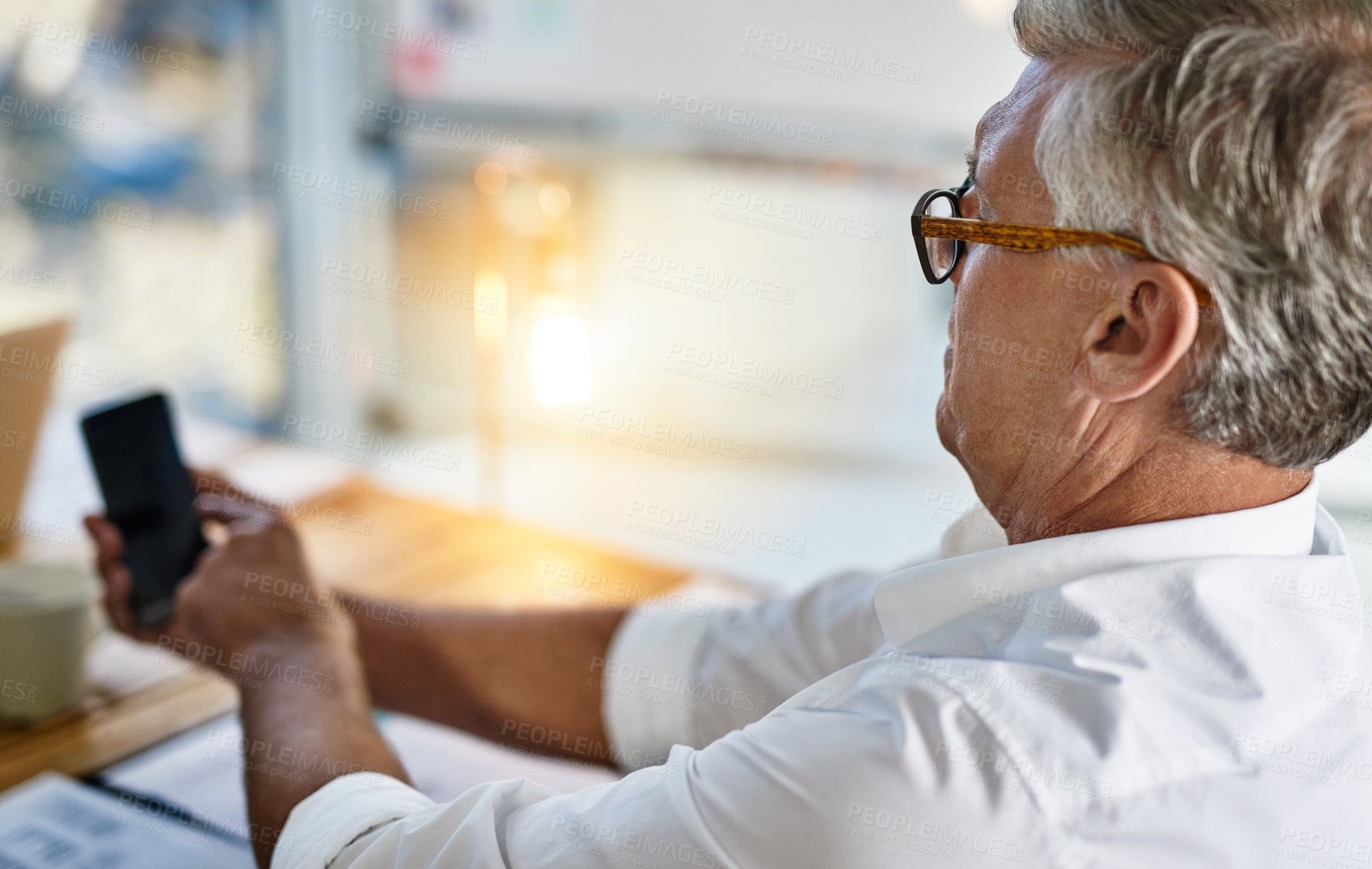 Buy stock photo Shot of a mature businessman struggling to use his cellphone in the office