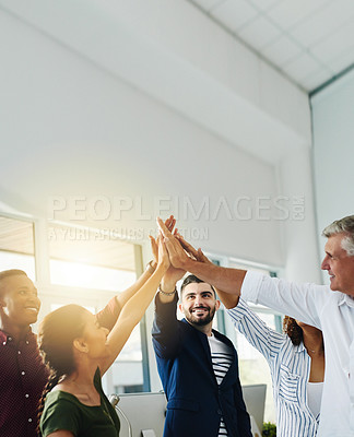 Buy stock photo Group of business people doing high five together while standing inside an office with sun flare and copy space. Team of colleagues, coworkers and employees celebrating teamwork and stacking hands