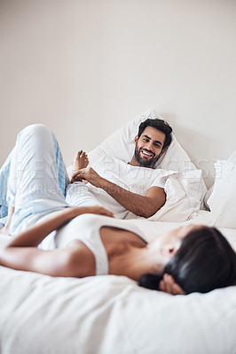 Buy stock photo Shot of a young couple lying on a bed together at home