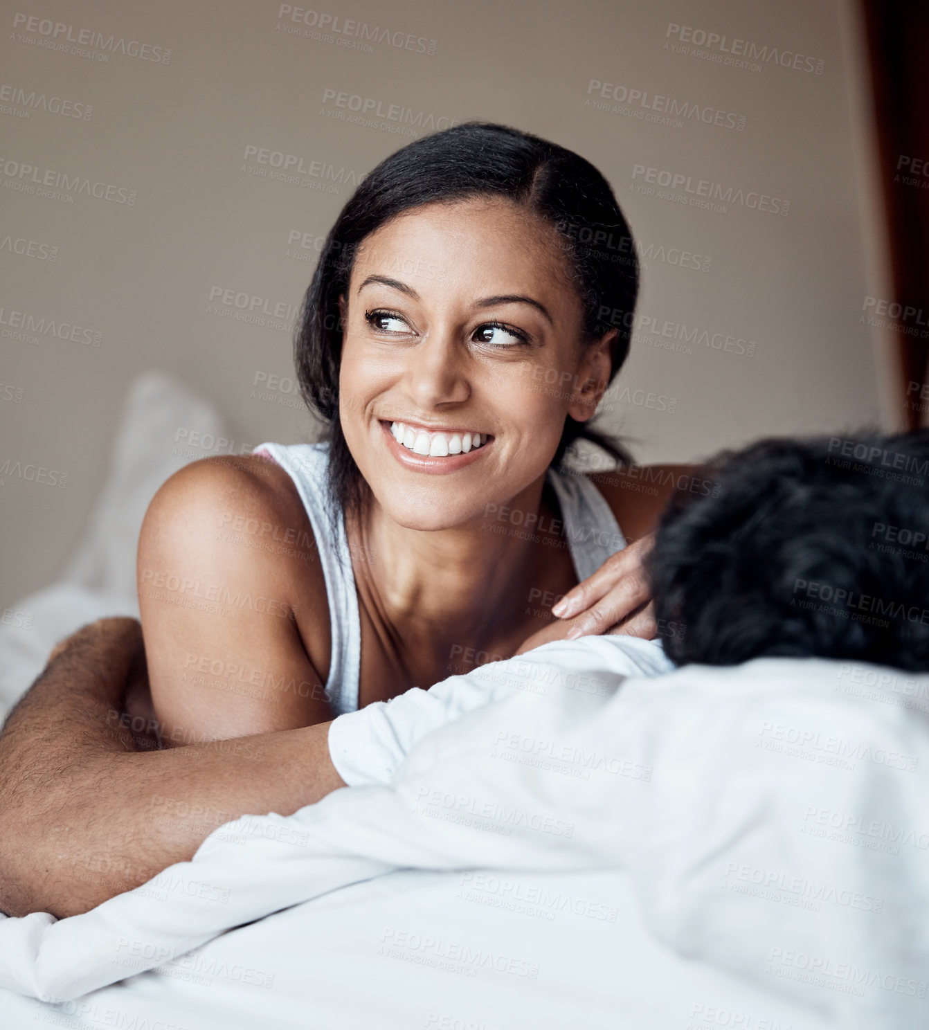 Buy stock photo Shot of a young woman lying on a bed with her husband at home