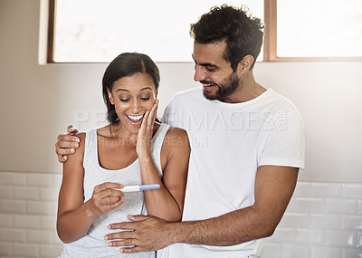 Buy stock photo Shot of a young couple feeling happy after taking a pregnancy test at home