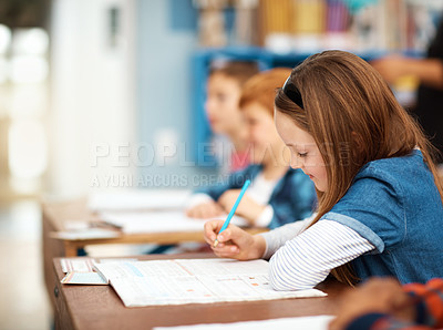 Buy stock photo Shot of an elementary school girl working alongside her peers in class