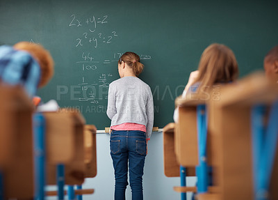Buy stock photo Rear view shot of an elementary school girl writing on the chalkboard in class