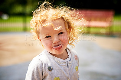 Buy stock photo Portrait of an adorable little girl sticking her tongue out outdoors