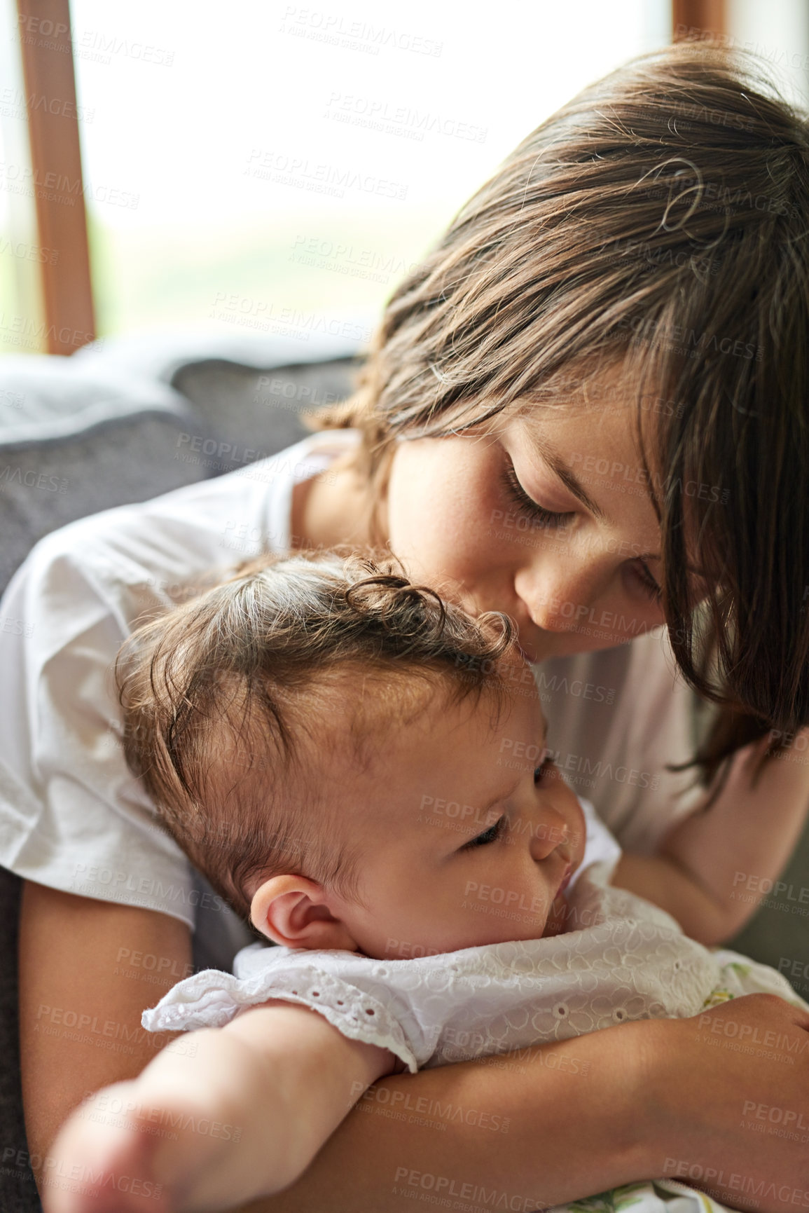 Buy stock photo Children, baby and relax with sister on sofa for love, care and bonding together on weekend. Family, house and girl with infant sibling in living room for development, growth and safety in morning