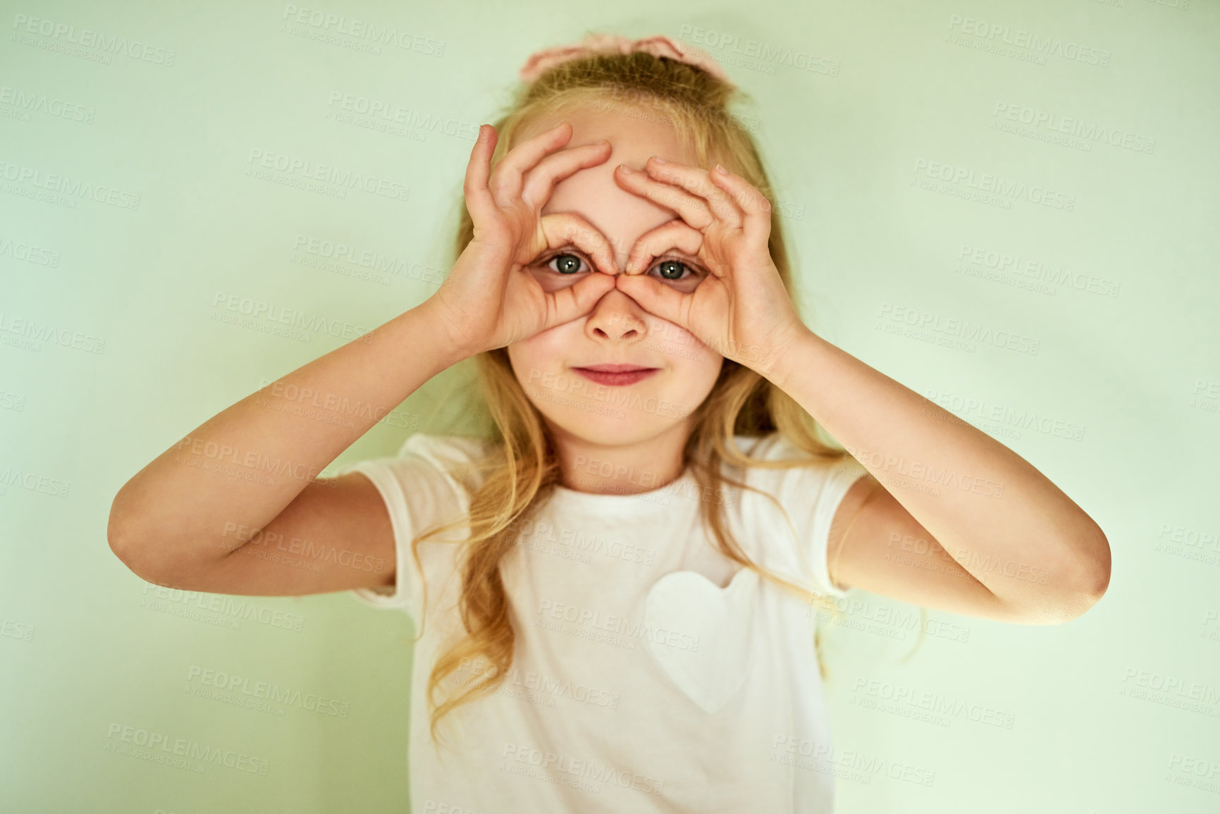 Buy stock photo Portrait, child and hand binoculars on eyes for fun, silly face and looking on studio background. Young girl, gesture and playful with glasses emoji for comedy, joke and facial expression with smile