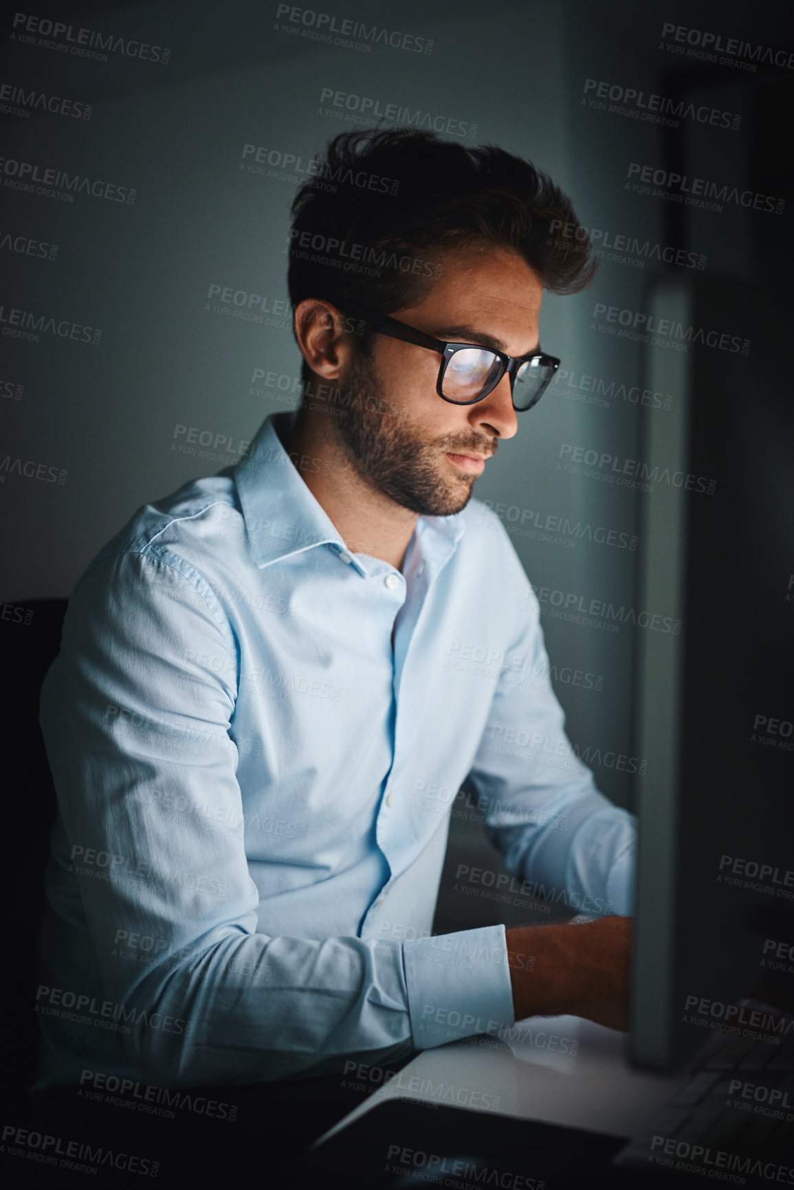 Buy stock photo Shot of a young businessman working late on a computer in an office
