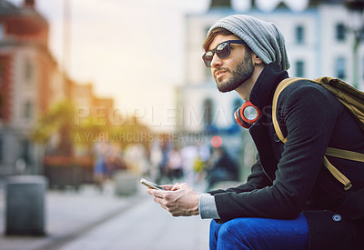 Buy stock photo Shot of a young man using his mobile phone while out in the city