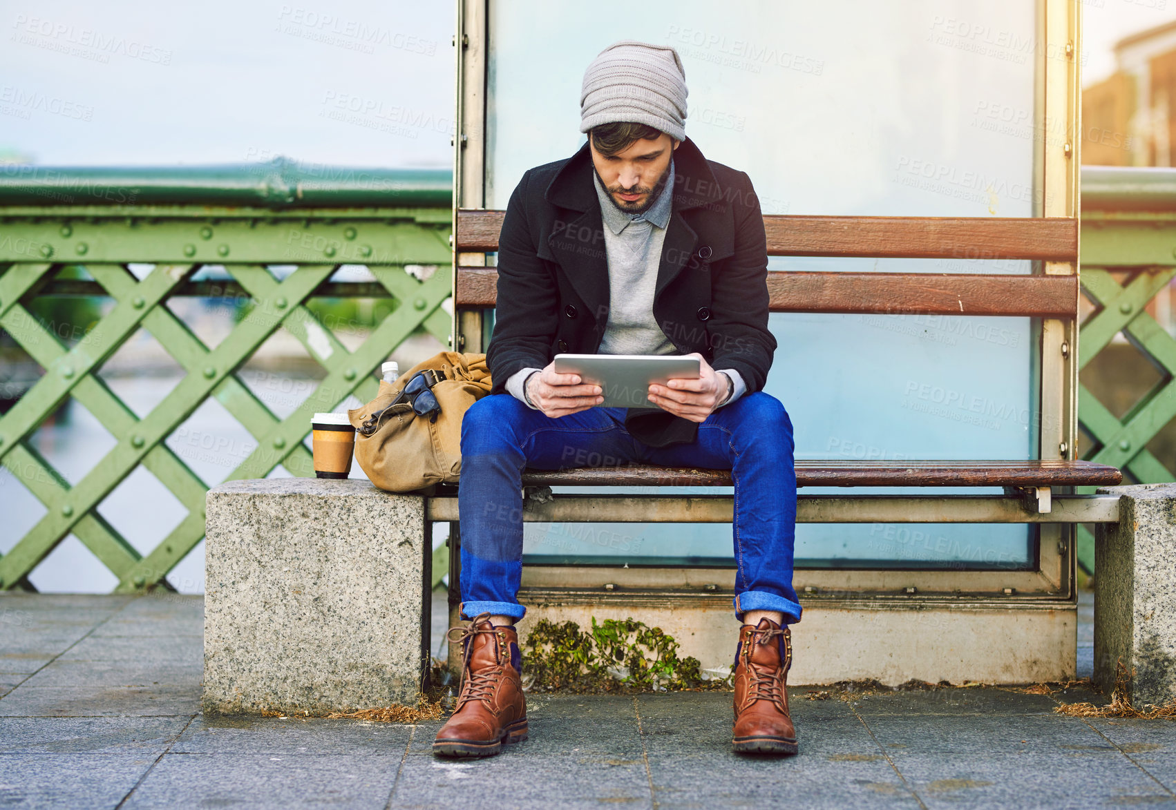 Buy stock photo Man, tablet and waiting in city for travel, social media and communication with backpack on holiday. Male person, tech and bus stop in urban town for commute, tourism and web with break on vacation