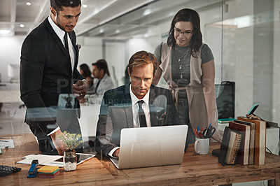 Buy stock photo Cropped shot of three business colleagues working together on a laptop in their office