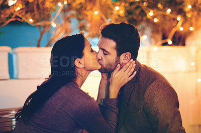 Buy stock photo Cropped shot of an affectionate young couple kissing while having a romantic dinner in a restaurant