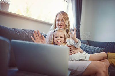 Buy stock photo Shot of an adorable little girl using a laptop with her mother on the sofa at home