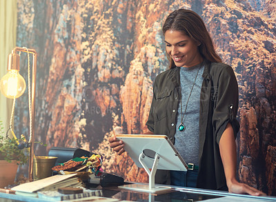 Buy stock photo Cropped shot of an attractive young woman working on a tablet behind the checkout counter in her store