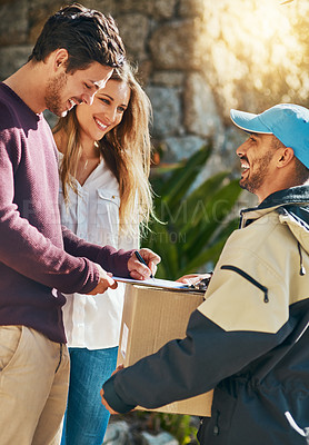 Buy stock photo Shot of a courier making a delivery to a young couple