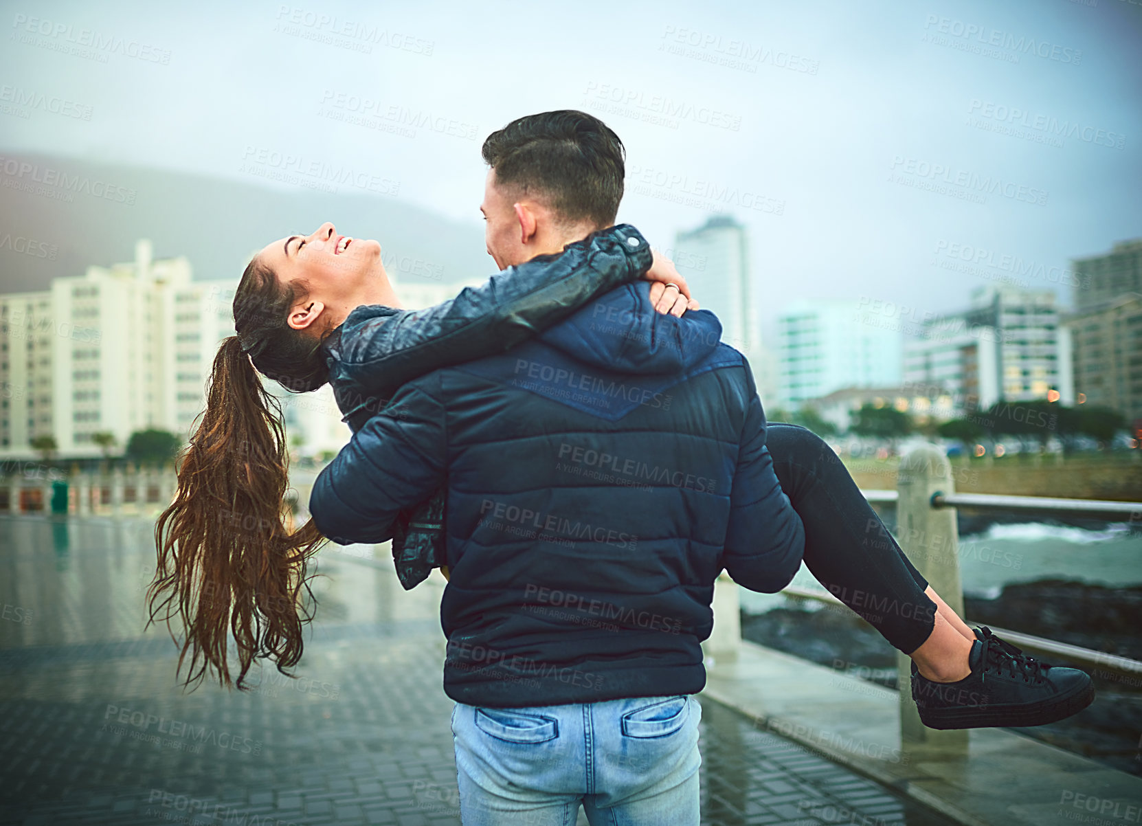 Buy stock photo Shot of a young man romantically carrying his girlfriend outdoors