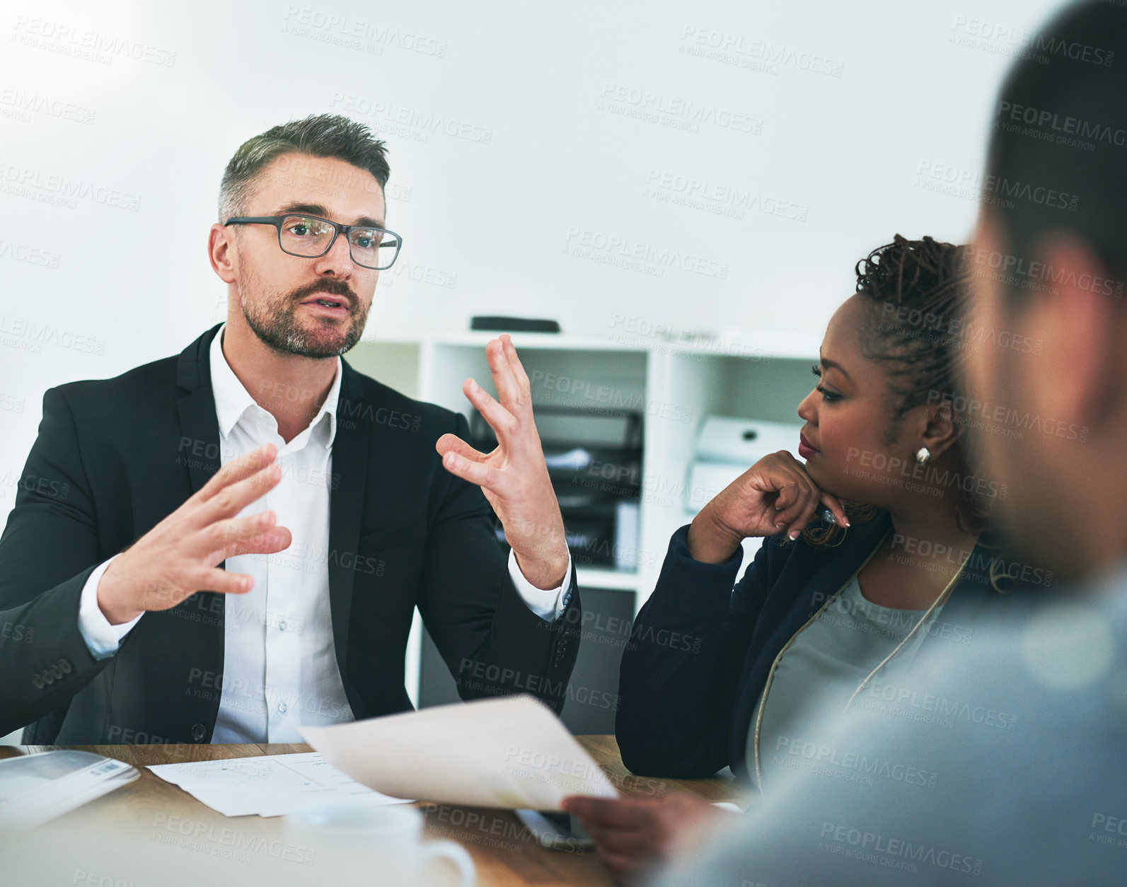 Buy stock photo Cropped shot of a group of corporate colleagues sitting in the boardroom during a meeting