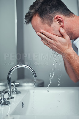 Buy stock photo Shot of a young man washing his face in the bathroom at home
