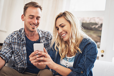 Buy stock photo Shot of a young couple using a cellphone at home