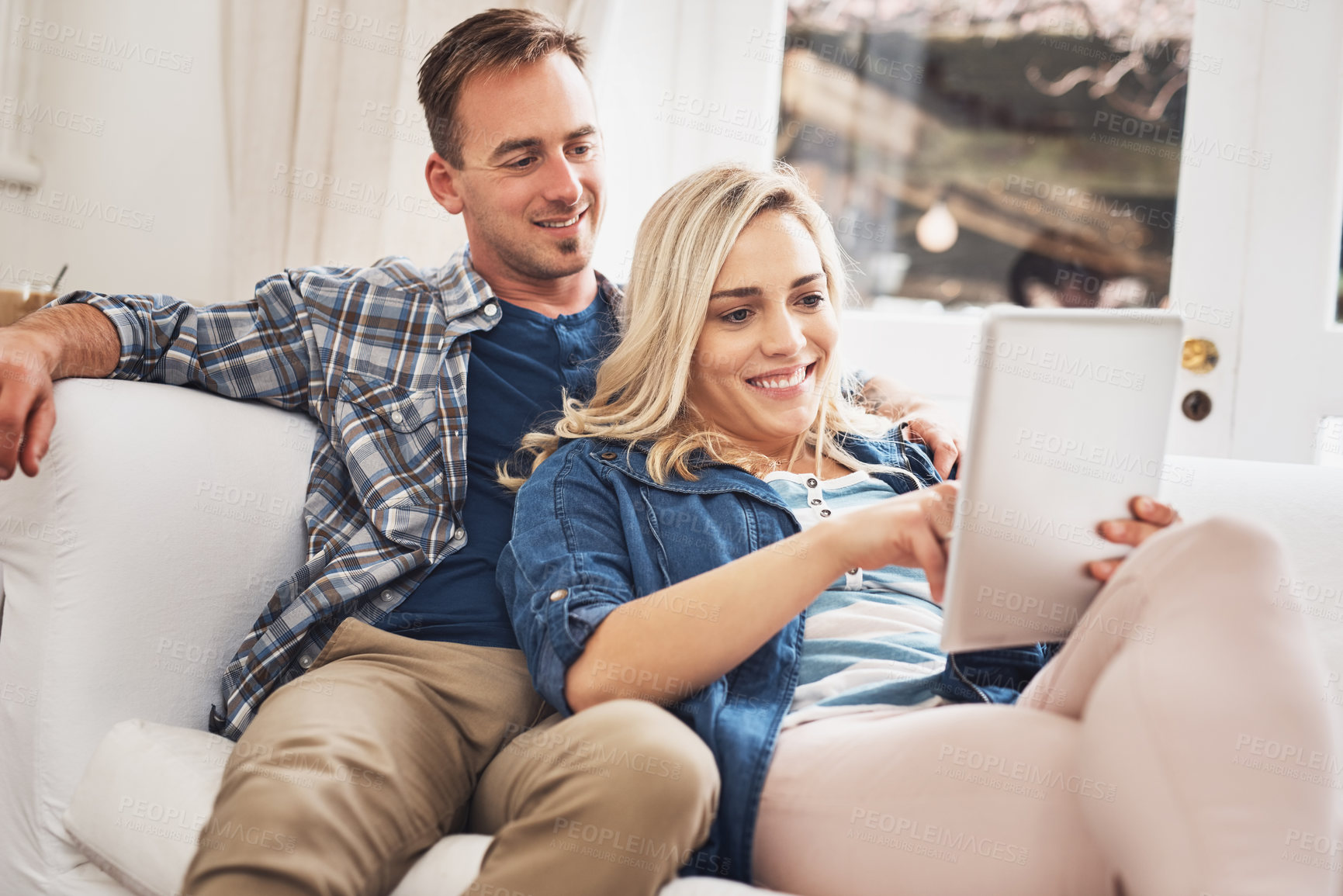 Buy stock photo Love, relax and tablet with couple on sofa in living room of home for accommodation search together. Internet, online booking and smile of happy man and woman in apartment for travel confirmation