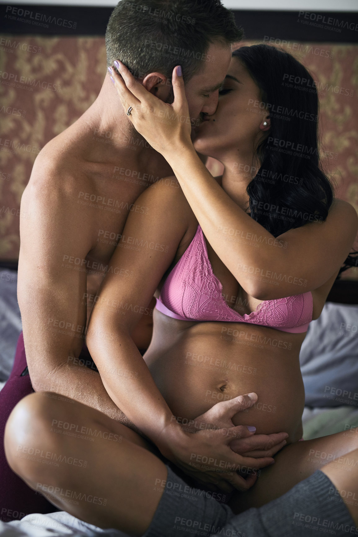 Buy stock photo Pregnancy, couple and hand on stomach with kiss, touch and safety in bedroom. Future parents, love and woman in underwear for growth, maternity and passion for protection or feeling baby kick in home