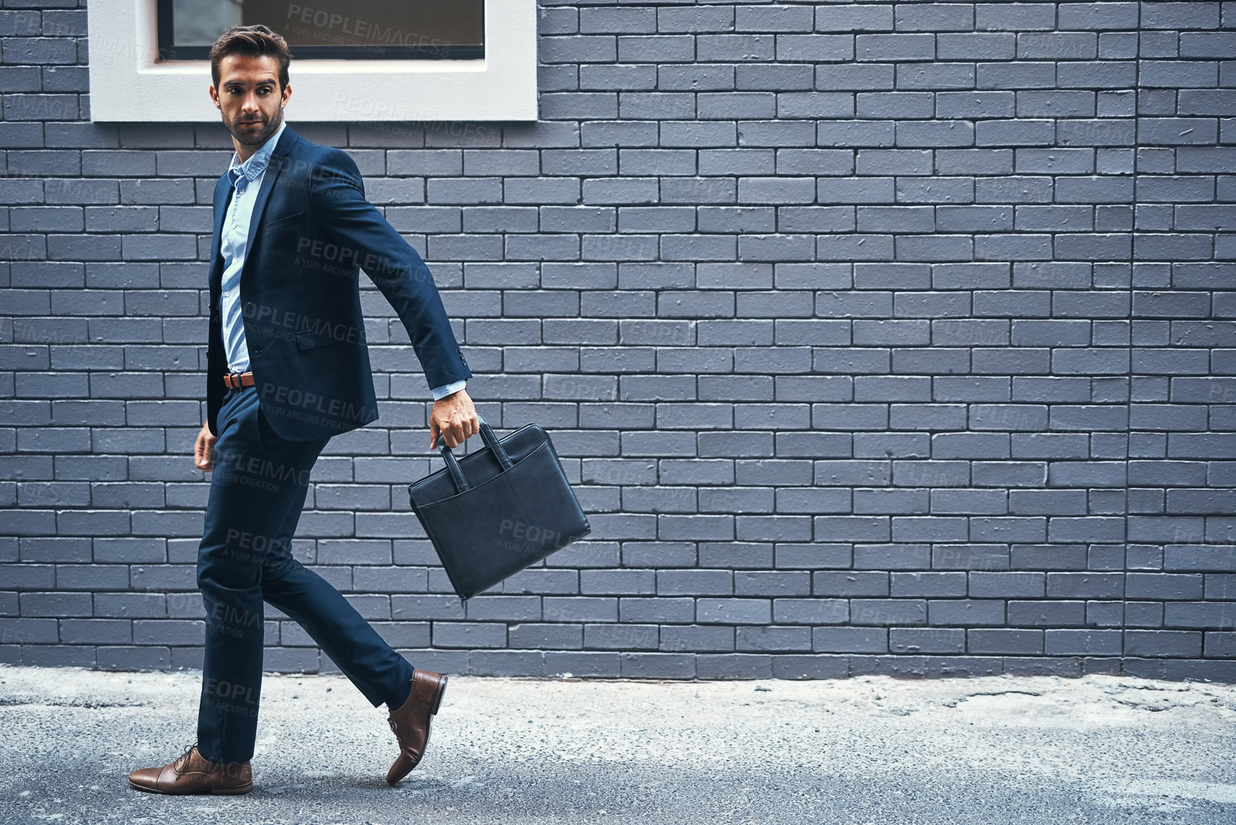 Buy stock photo Man, walking and brick wall in city for business with briefcase, work commute, and corporate company. Male executive, bag and urban background for banking career with travel, professional and street