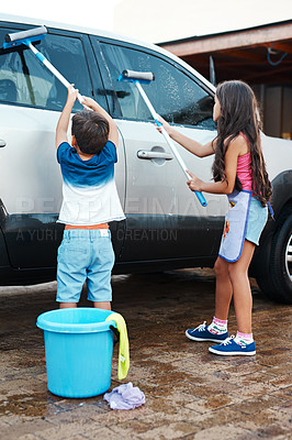 Buy stock photo Children, clean and home or washing car, kids and motor vehicle with equipment for windows. Siblings, driveway and helping with responsibility together on weekend, outdoor for chore with bucket