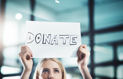 Buy stock photo Donate, volunteer and give back to the community with a sign in the hands of a young woman inside. Closeup of a poster with text looking for welfare aid, donations and contributions to society