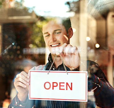 Buy stock photo Open, sign and waiter at door of cafe for small business, message or beginning of hospitality service. Coffee shop, smile and man with board by window for restaurant, information or start of work day