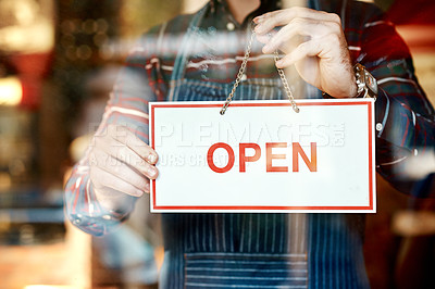 Buy stock photo Closeup shot of an unrecognizable man hanging up an open sign in a shop window